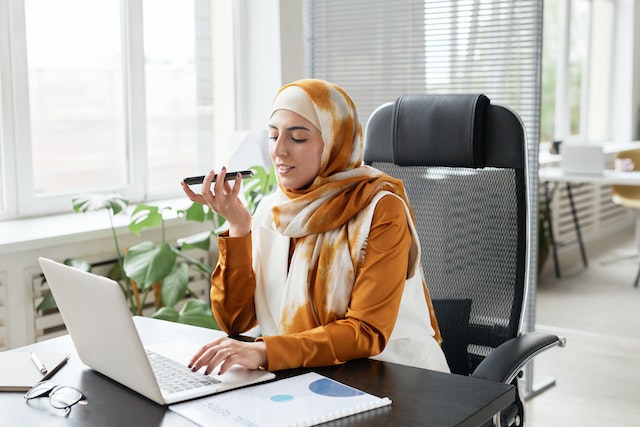 property manager sitting at their desk speaking on the phone while taking notes on their computer 